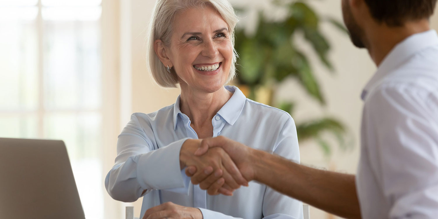 A woman shaking hands with a man - Business Succession Planning