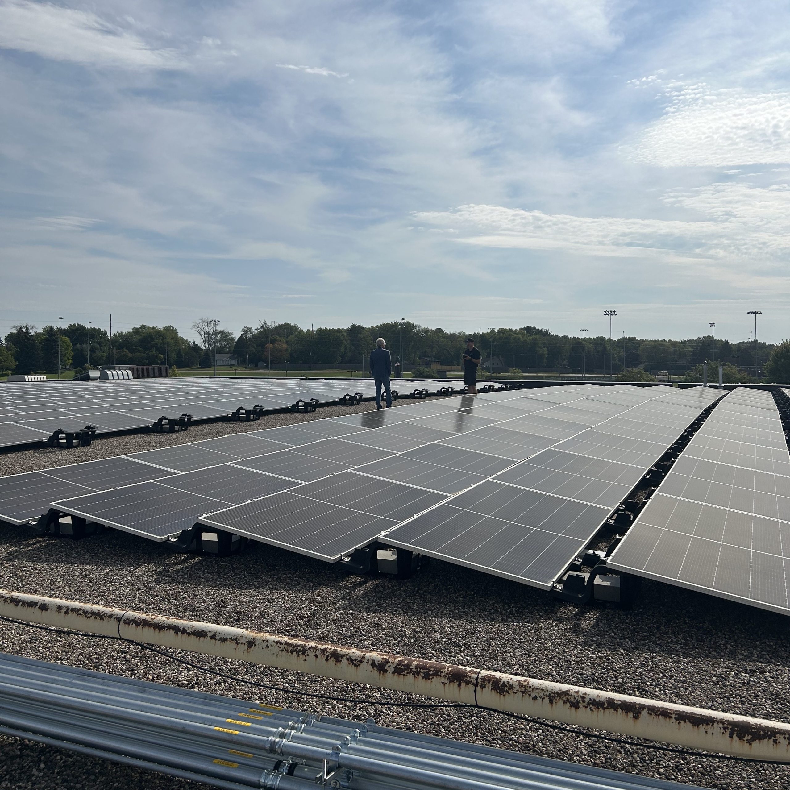 a man standing on top of a roof next to rows of solar panels - Cooperative energy futures 