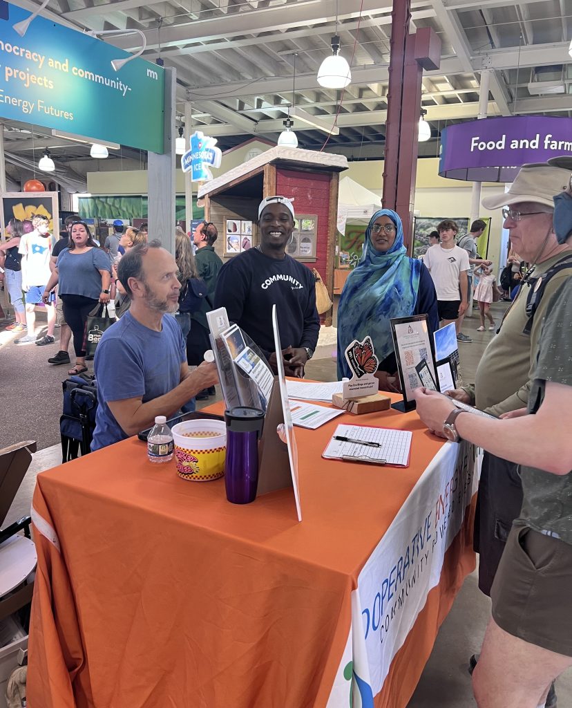 a group of people standing around a table- Cooperative energy futures 