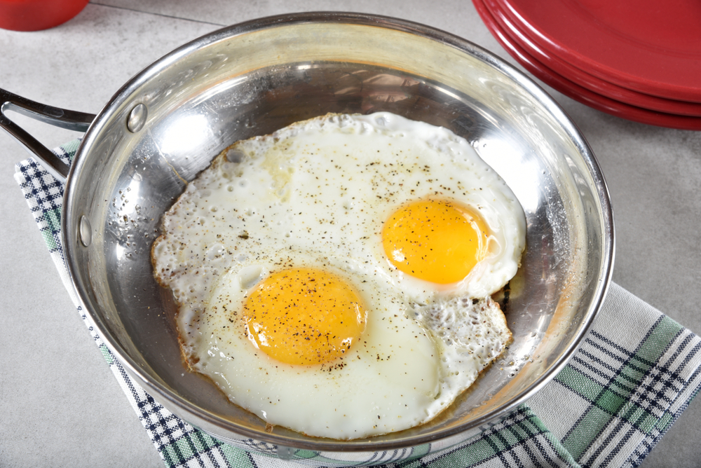 Two fried eggs in a stainless steel pan.